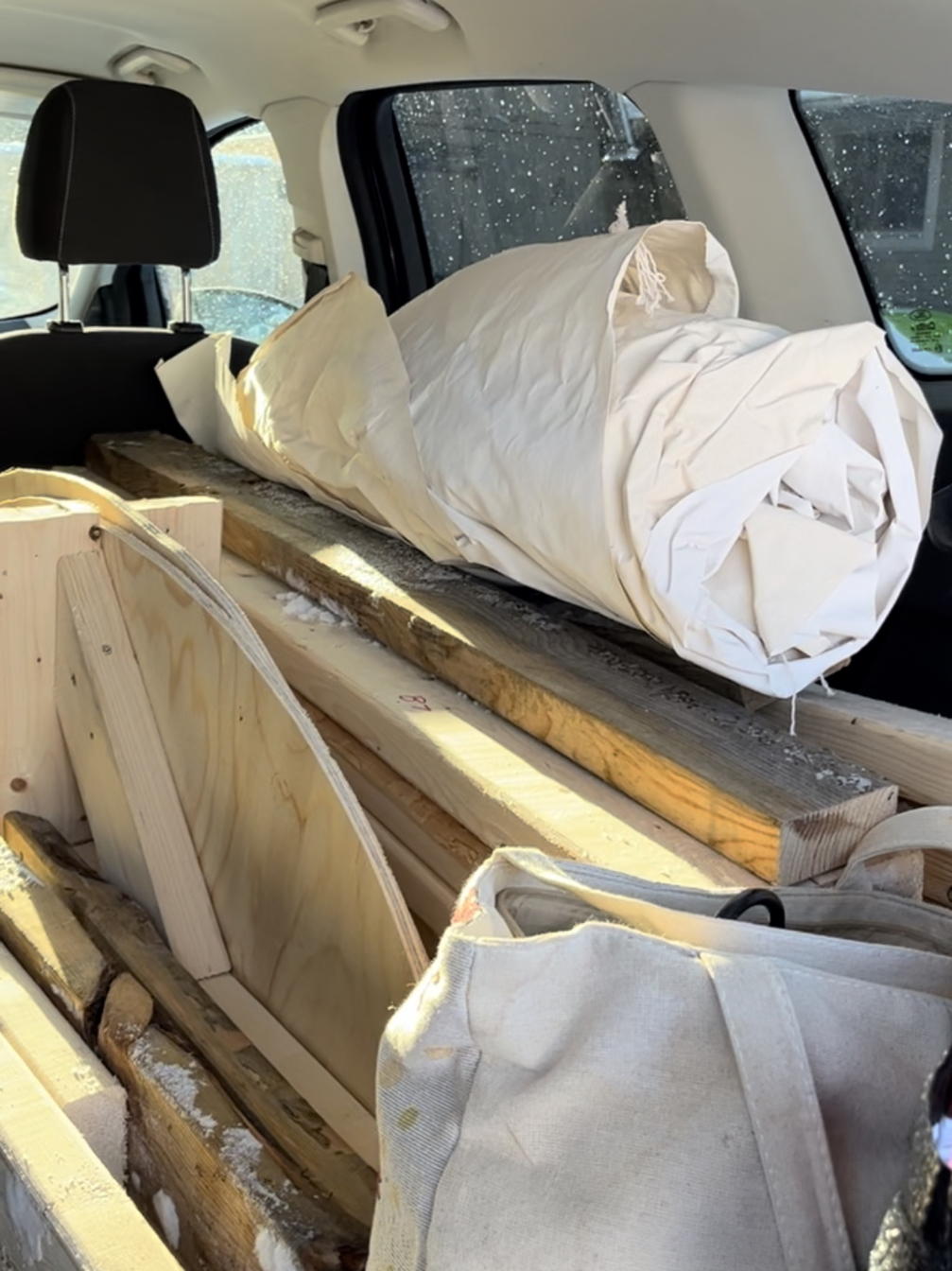 À l'arrière d'une voiture, des morceaux de bois et de la toile : c'est la sculpture démontée.