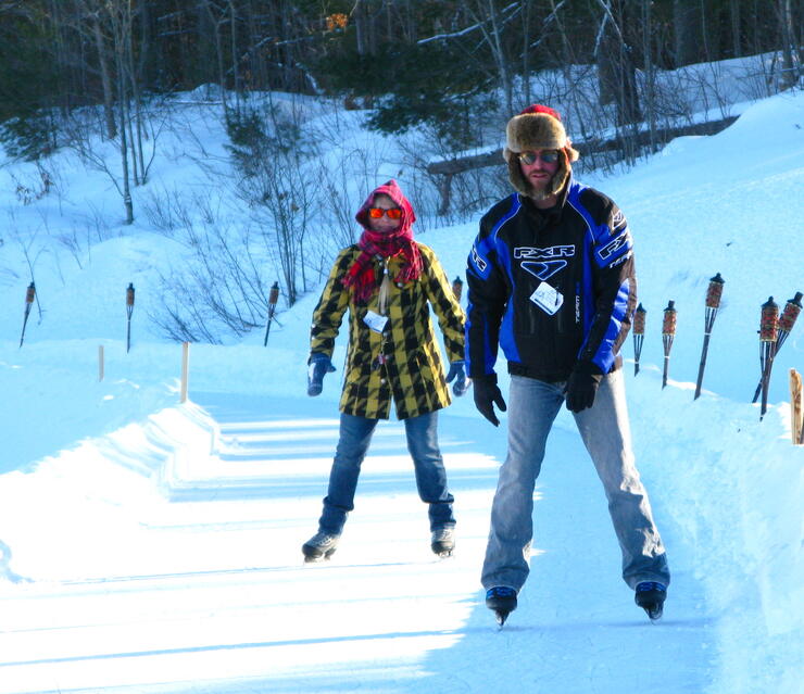 A man and a woman skating on an outdoor trail 